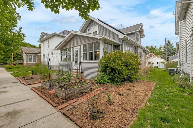 851 Watson Ave, Saint Paul, MN 55102 - view of front of house featuring a garden, a sunroom, a front yard, and central AC unit