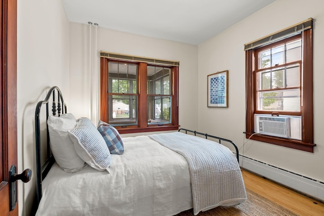 851 Watson Ave, Saint Paul, MN 55102 - bedroom featuring a baseboard radiator, wood finished floors, multiple windows, and cooling unit