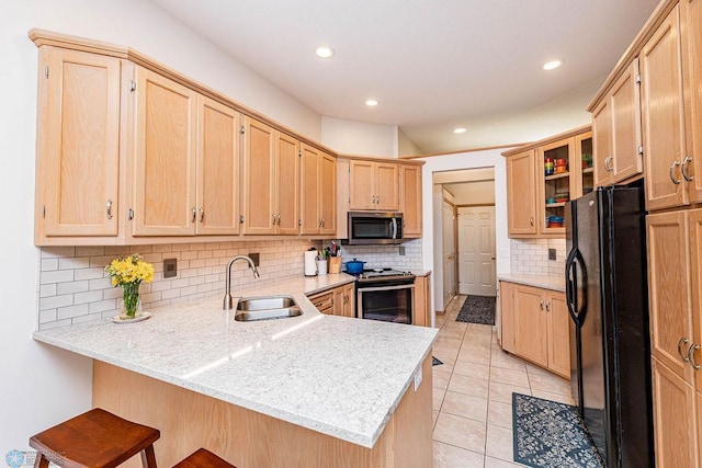 kitchen with light brown cabinetry, a peninsula, stainless steel appliances, and a sink