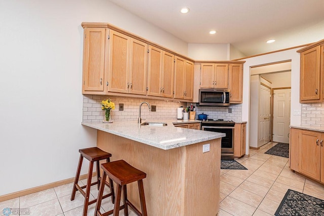 kitchen with tasteful backsplash, a kitchen breakfast bar, a peninsula, stainless steel appliances, and a sink