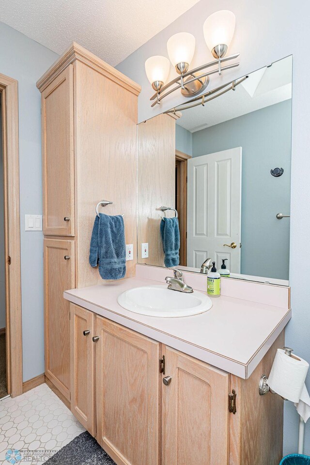 bathroom featuring a notable chandelier, a textured ceiling, vanity, and baseboards