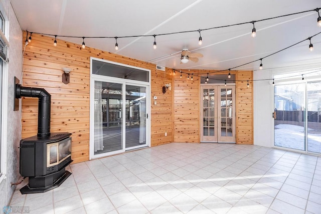 interior space featuring wood walls, rail lighting, french doors, a wood stove, and a ceiling fan