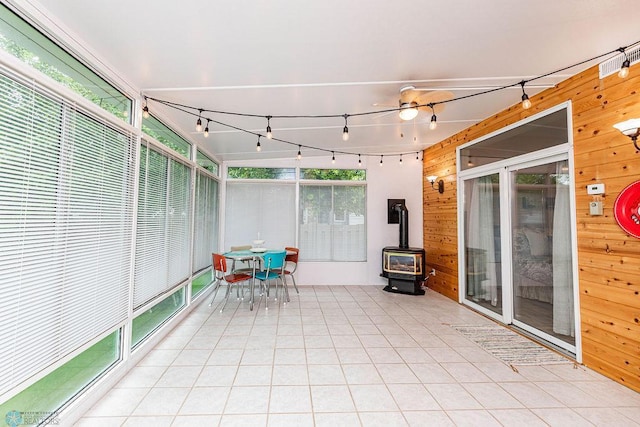 unfurnished sunroom featuring wood walls, a wood stove, and tile patterned flooring