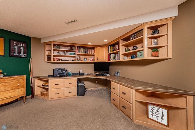 home office with built in desk, light colored carpet, and visible vents