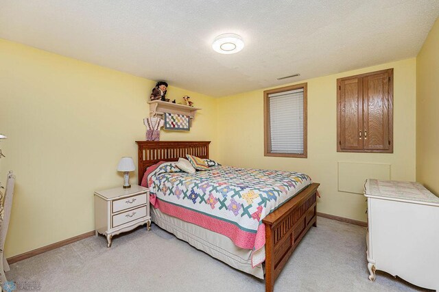 bedroom featuring baseboards, light carpet, and a textured ceiling