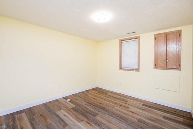 empty room with wood finished floors, baseboards, and a textured ceiling