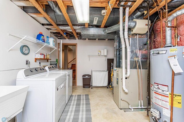 washroom featuring gas water heater, washing machine and dryer, laundry area, and a sink