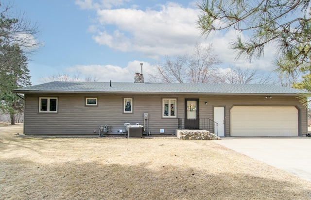 17639 Gayle Dr, Little Falls, MN 56345 - back of property with a shingled roof, an attached garage, a chimney, central air condition unit, and driveway