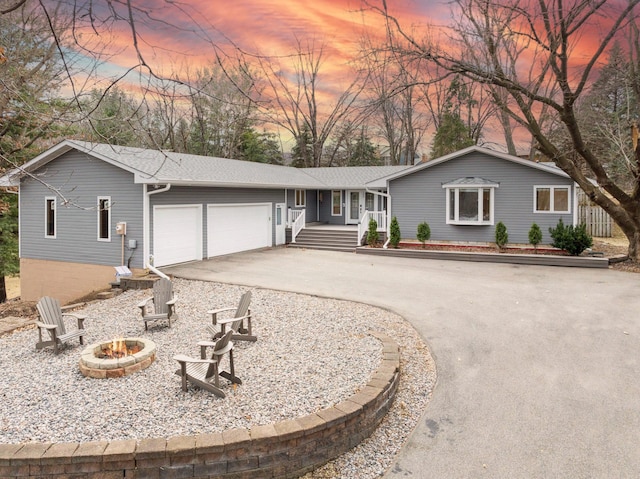 single story home featuring an outdoor fire pit, a porch, an attached garage, and concrete driveway
