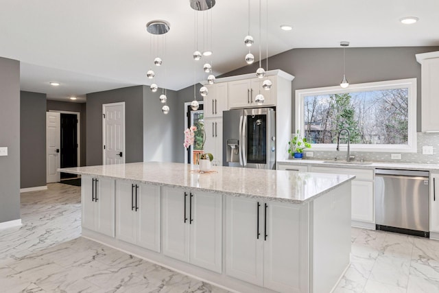kitchen featuring marble finish floor, a kitchen island, appliances with stainless steel finishes, a sink, and backsplash