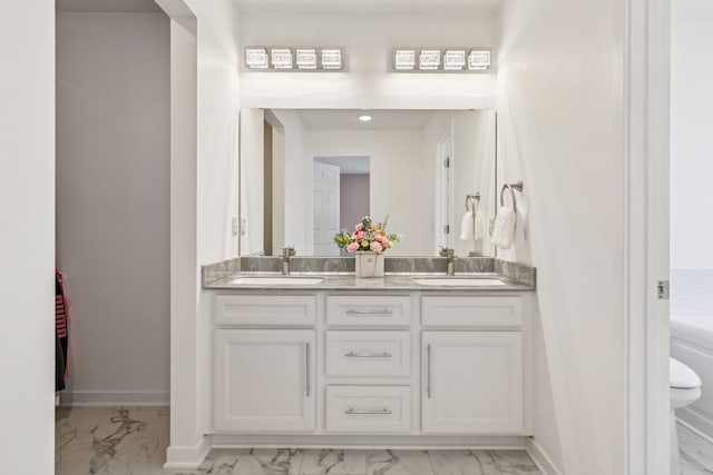 full bath with marble finish floor, baseboards, double vanity, and a sink