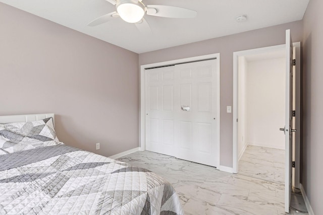 bedroom with baseboards, marble finish floor, ceiling fan, and a closet