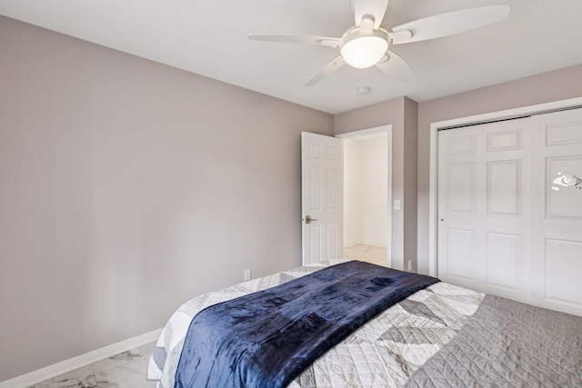 bedroom with baseboards, marble finish floor, a closet, and a ceiling fan