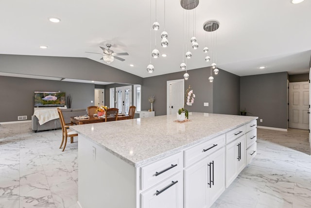 kitchen with marble finish floor, light stone countertops, a ceiling fan, lofted ceiling, and a center island