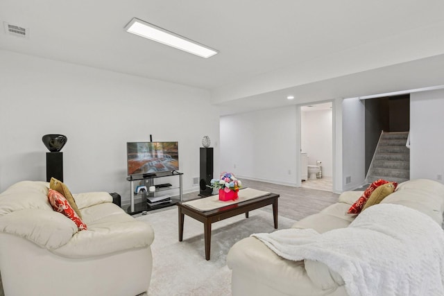 living room featuring stairs, visible vents, light wood-style floors, and baseboards