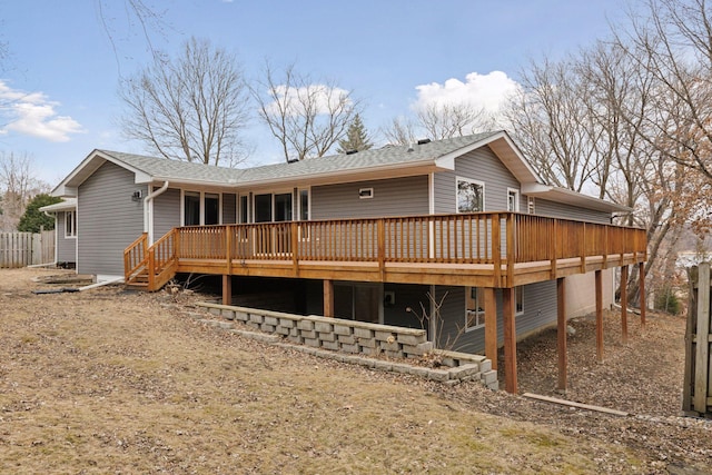 rear view of house featuring a shingled roof, fence, and a deck