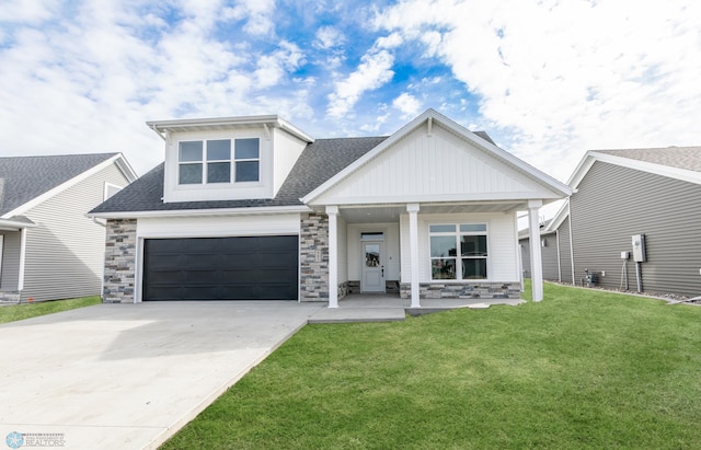 craftsman inspired home featuring roof with shingles, stone siding, a porch, a front yard, and driveway