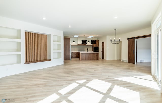 662 Rania Way W, West Fargo, ND 58078 - unfurnished living room featuring a barn door, light wood-style floors, a chandelier, a sink, and recessed lighting