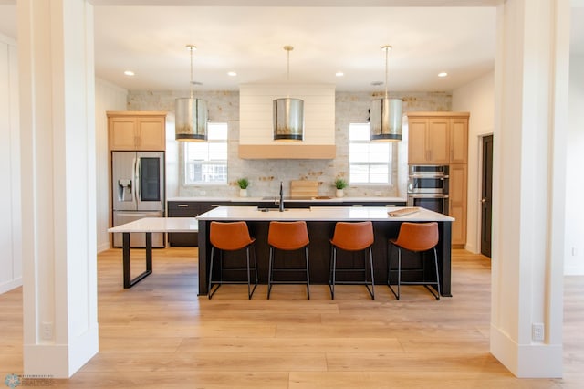 662 Rania Way W, West Fargo, ND 58078 - kitchen with stainless steel appliances, light brown cabinets, wall chimney range hood, and a center island with sink