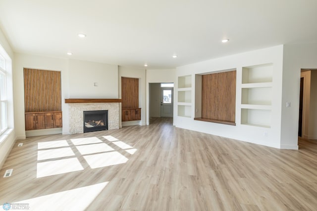 662 Rania Way W, West Fargo, ND 58078 - unfurnished living room featuring a stone fireplace, light wood-style flooring, recessed lighting, and built in features