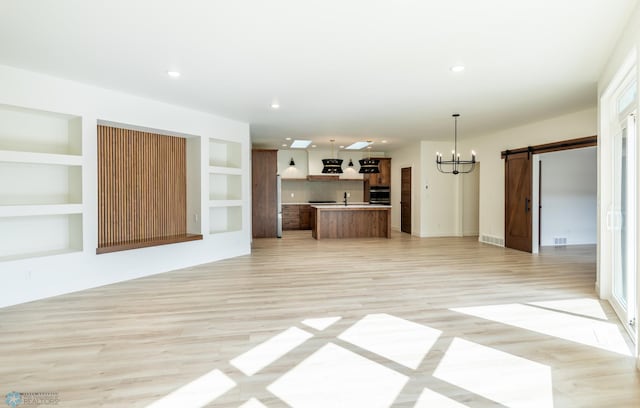 662 Rania Way W, West Fargo, ND 58078 - unfurnished living room with a barn door, a chandelier, light wood-style flooring, and recessed lighting