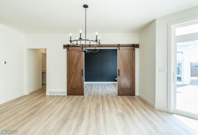 662 Rania Way W, West Fargo, ND 58078 - unfurnished dining area with a chandelier, a barn door, and light wood-style flooring