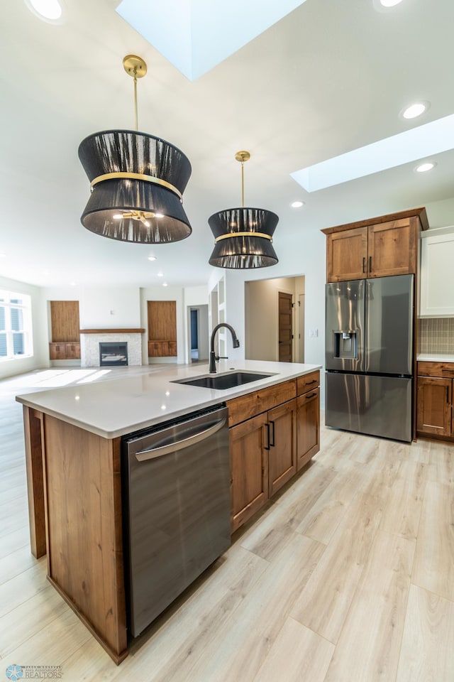 662 Rania Way W, West Fargo, ND 58078 - kitchen featuring a skylight, stainless steel appliances, light wood-type flooring, an island with sink, and light countertops