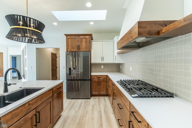 662 Rania Way W, West Fargo, ND 58078 - kitchen featuring appliances with stainless steel finishes, range hood, light countertops, a skylight, and light wood-style floors