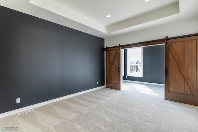 662 Rania Way W, West Fargo, ND 58078 - unfurnished bedroom with a barn door, a raised ceiling, light carpet, and recessed lighting