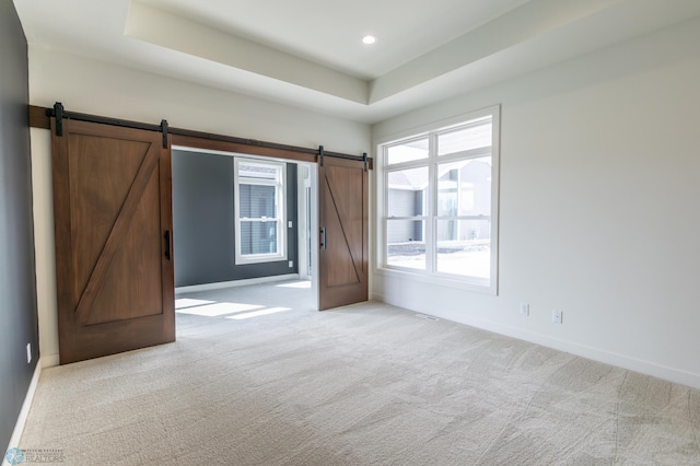 662 Rania Way W, West Fargo, ND 58078 - unfurnished bedroom with a barn door, light carpet, a tray ceiling, and recessed lighting