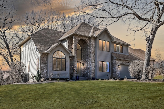 view of front of house with a shingled roof, a front yard, and brick siding