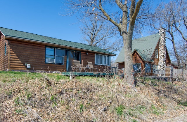 view of front of property with a deck, a shingled roof, and a chimney