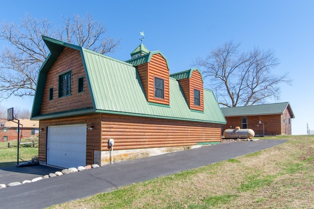 view of side of property featuring metal roof, an attached garage, and a gambrel roof