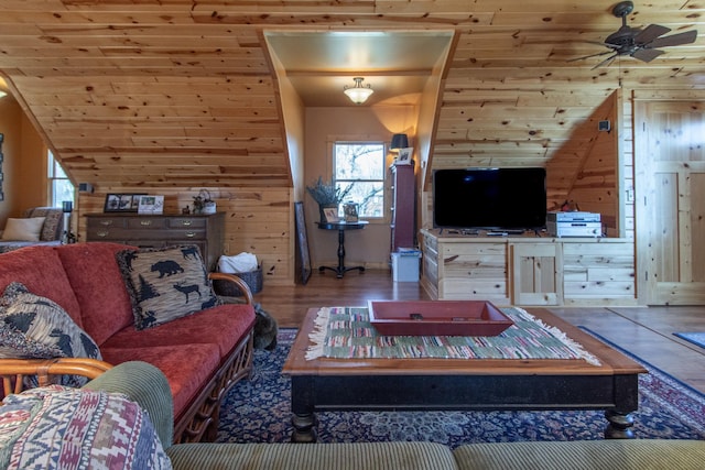 living room with wood walls, ceiling fan, wood finished floors, and a healthy amount of sunlight