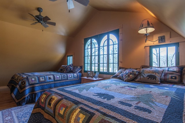 bedroom with a ceiling fan, vaulted ceiling, multiple windows, and wood finished floors