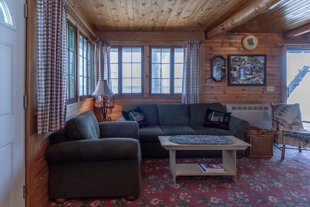 living area with wooden walls, wooden ceiling, and beam ceiling