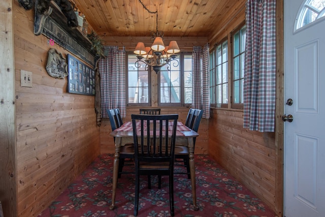 dining area with wooden walls, a notable chandelier, wooden ceiling, and a healthy amount of sunlight