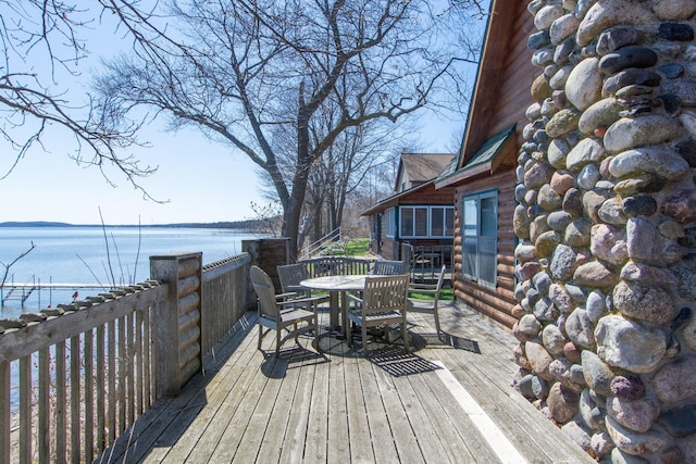 wooden terrace with a water view and outdoor dining space