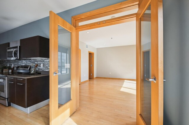 3104 Lake St Unit 202, Minneapolis, MN 55416 - kitchen featuring appliances with stainless steel finishes, light wood-style flooring, backsplash, modern cabinets, and dark brown cabinets