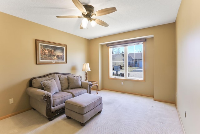 sitting room featuring a ceiling fan, light colored carpet, and baseboards