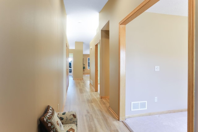 hall with light wood-style floors and baseboards