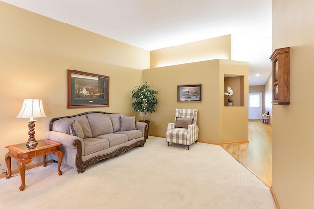 living area with baseboards and light colored carpet