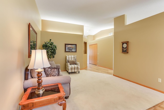 living area with lofted ceiling, baseboards, and light carpet