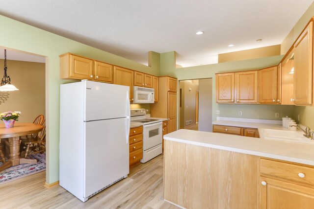 kitchen featuring white appliances, light brown cabinetry, a sink, light wood finished floors, and light countertops