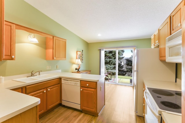 kitchen featuring white appliances, a sink, a peninsula, light wood-style flooring, and light countertops