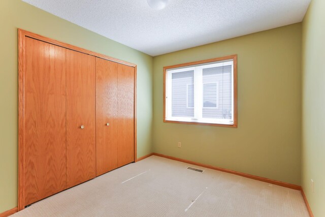 unfurnished bedroom with a closet, carpet flooring, baseboards, and a textured ceiling