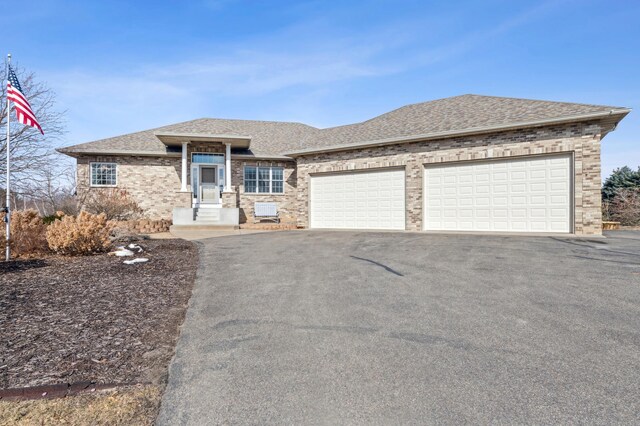 view of front of home with brick siding, a garage, driveway, and roof with shingles