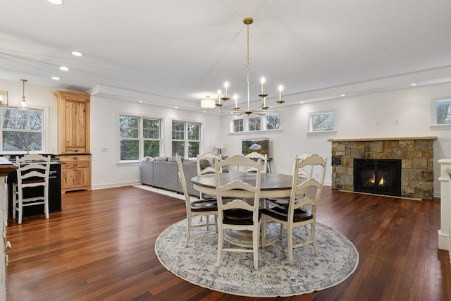 18975 Highland Ave, Deephaven, MN 55391 - dining space featuring dark wood-style floors, a chandelier, recessed lighting, a stone fireplace, and baseboards