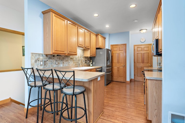 11102 16th St NE, Saint Michael, MN 55376 - kitchen featuring a peninsula, stainless steel appliances, light wood-type flooring, a breakfast bar area, and recessed lighting