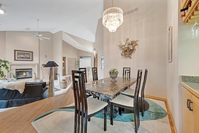 780 Virginia Shores Cir, Excelsior, MN 55331 - dining space with a ceiling fan, high vaulted ceiling, a glass covered fireplace, baseboards, and light wood-type flooring